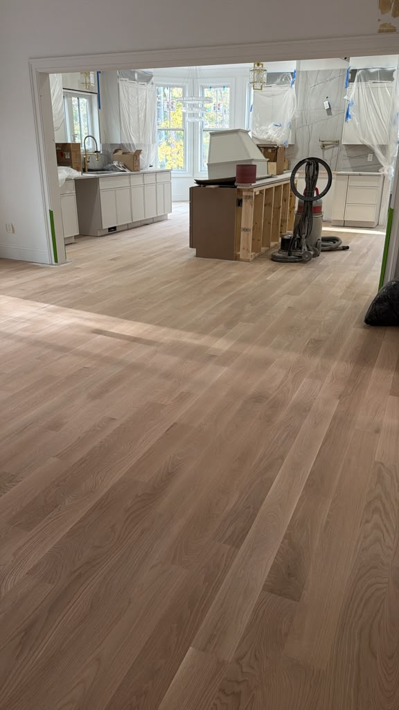 Light wood flooring extending into a kitchen under renovation