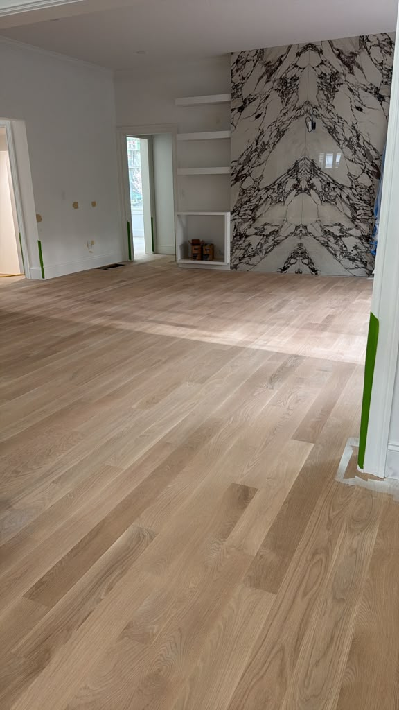 Light wood flooring in a living room with a veined feature wall